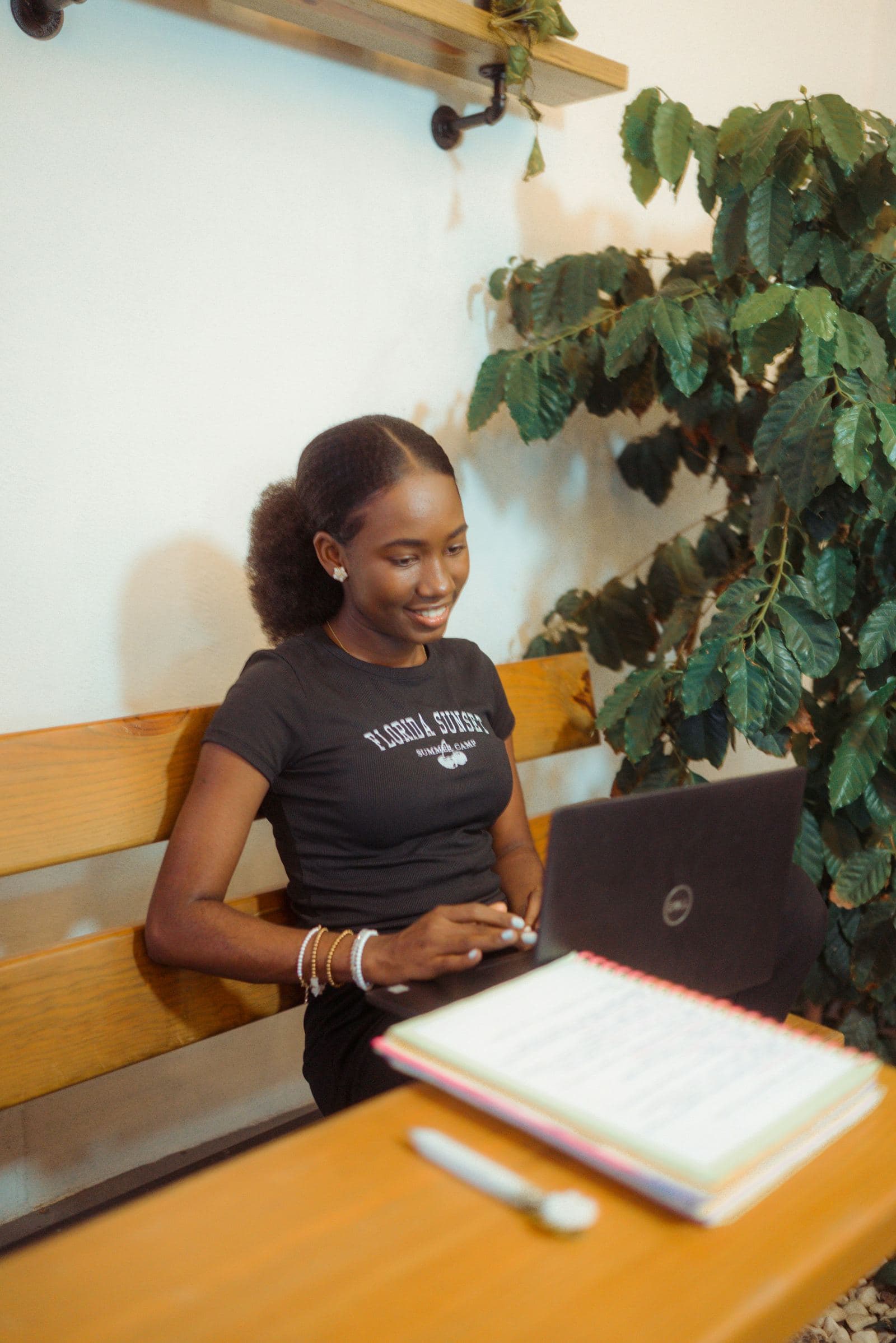 A learner working through a course on her laptop, notebook open beside her
